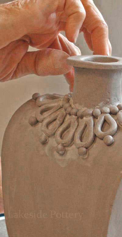 applying decorative clay coil to a pot