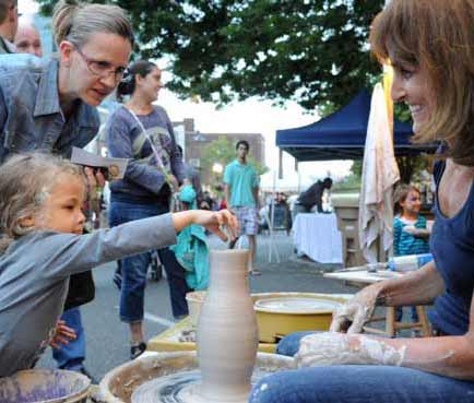 Tri-state area Art and Craft fair with children and adults trying pottery