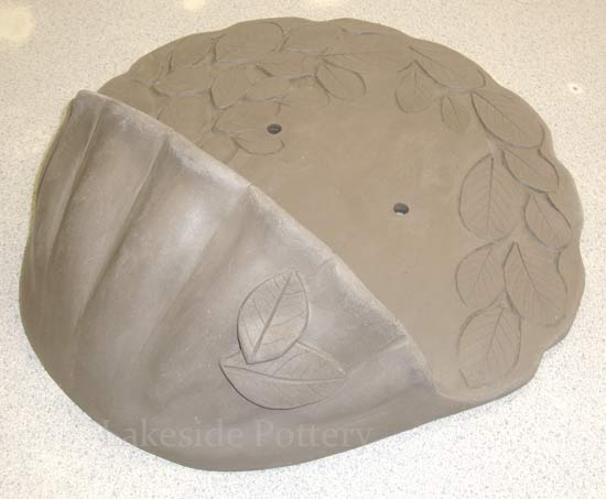 clay water font with carved leaves