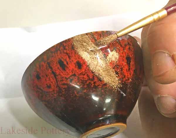 Use very soft brush to apply the gold powder over the lacquer